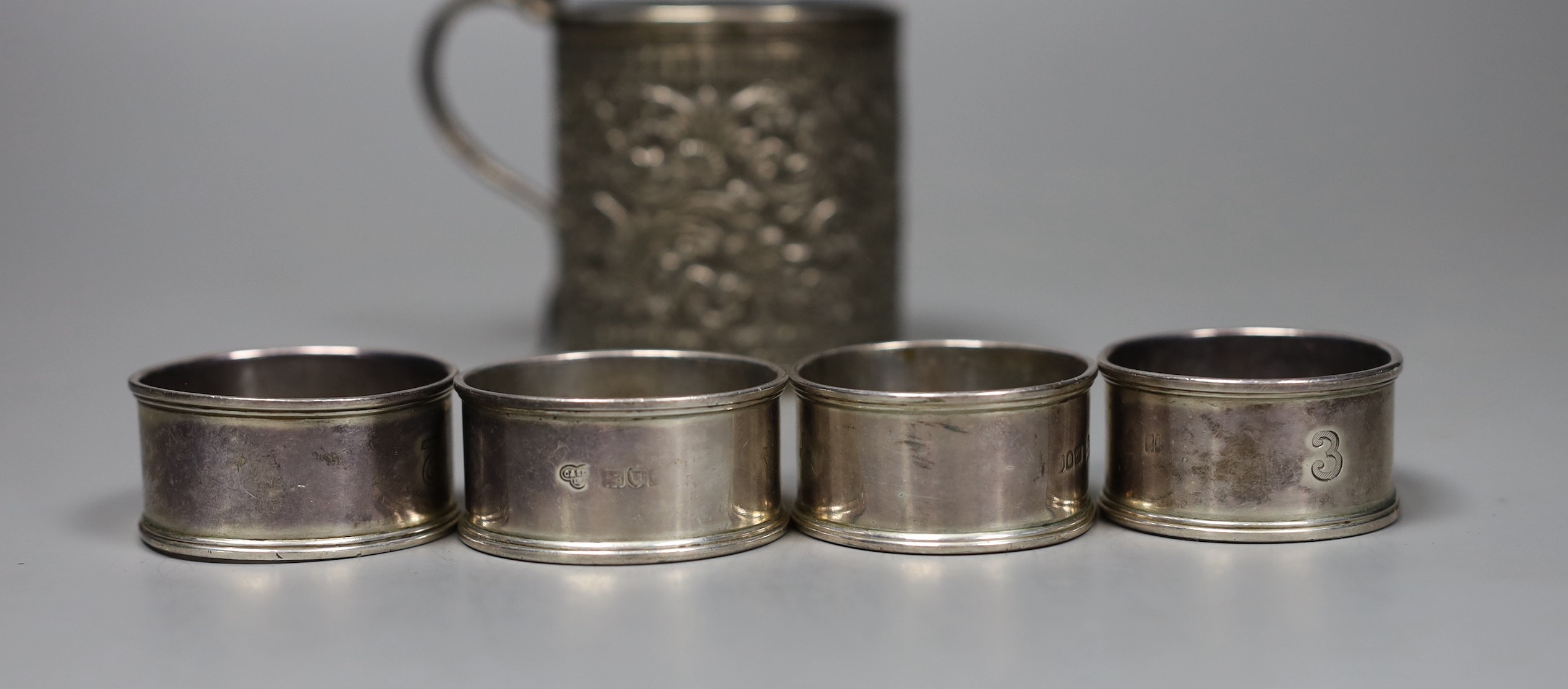 A 19th century Indian white metal christening can with cobra handle, a set of four silver napkin rings, two spoons and three mother of pearl handled butter knives.